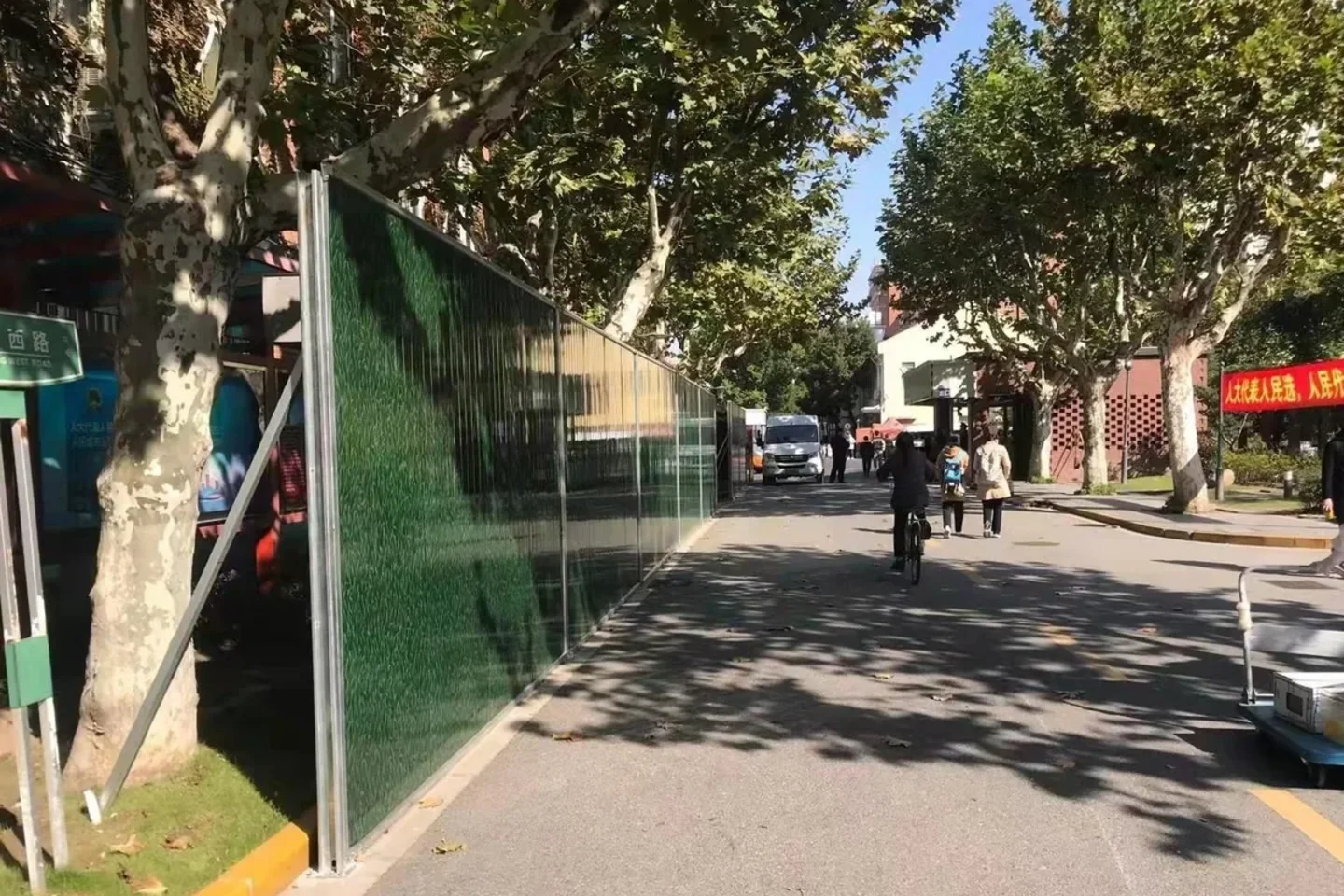 Green corrugated steel temporary hoarding along a generic street edge