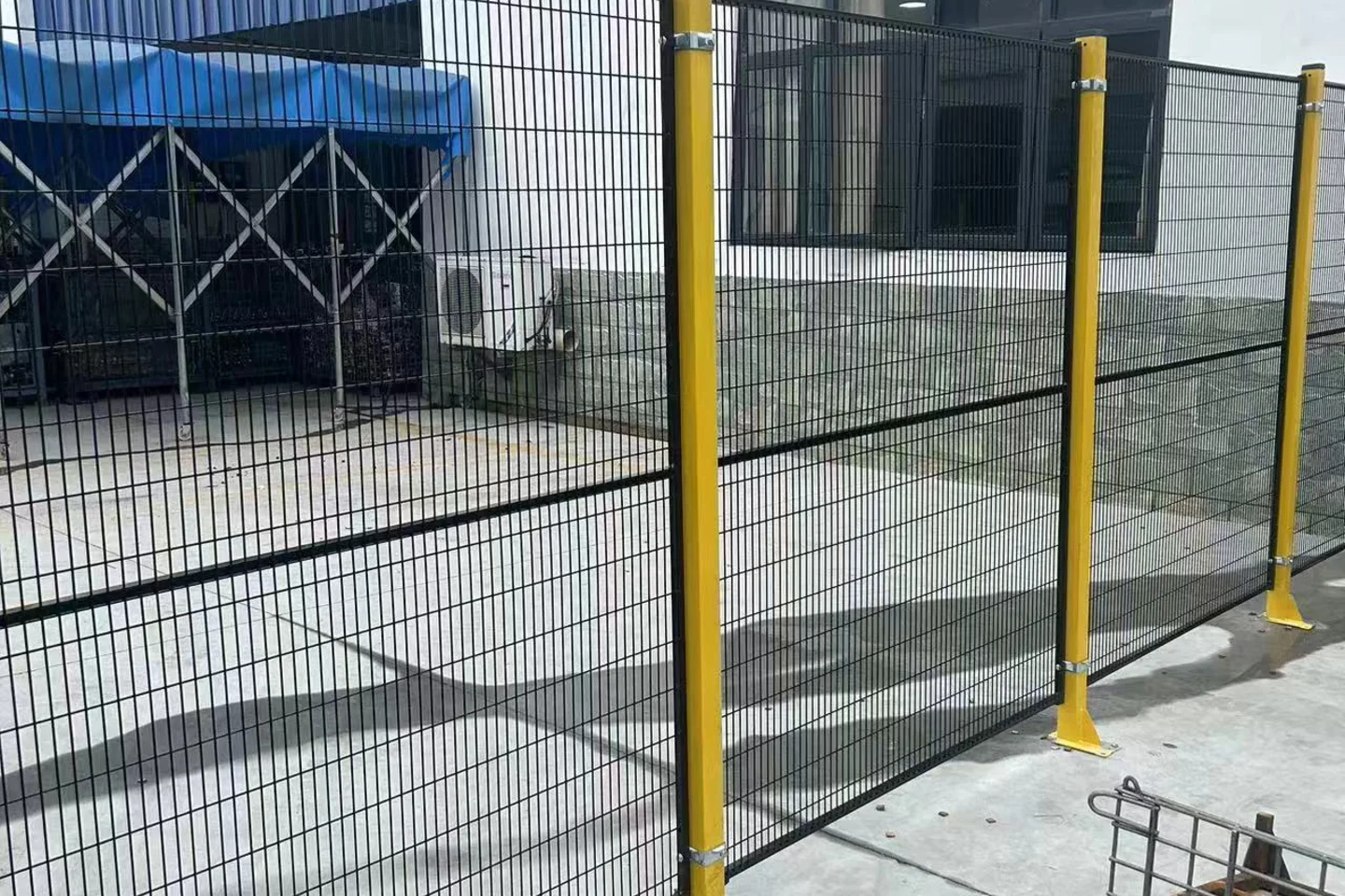 Black industrial equipment partition with yellow posts around a workshop zone