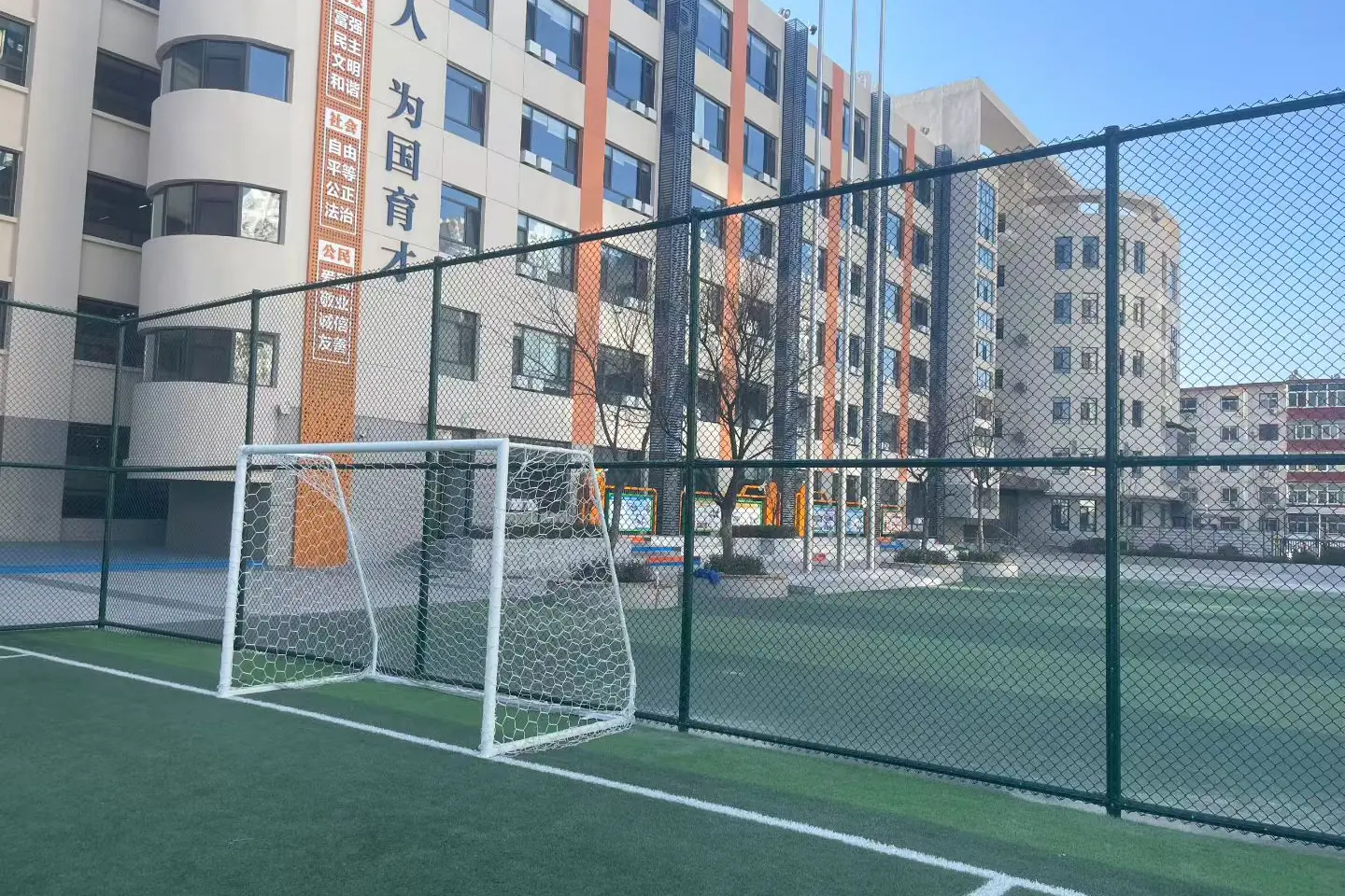Tall dark sports fence around a football pitch